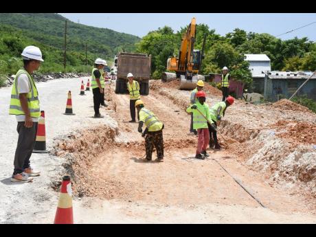 Workmen from China Harbour Engineering Company remove marl from a section of the Pamphret main road in St Thomas.