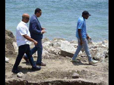 Prime Minister Andrew Holness (centre), James Robertson (left), member of parliament for St Thomas Western, and Robert Morgan (right), minister of works, walk along a section of the Roselle main road in St Thomas to examine sections of the roadway and reta