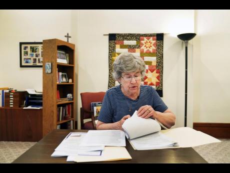 Sister Barbara McCracken looks through prior resolutions filed against various corporations, including Alphabet, Meta, Netflix and Chevron, at the Mount St Scholastica Benedictine monastery in Atchison, Kansas, on Tuesday, July 16, 2024.