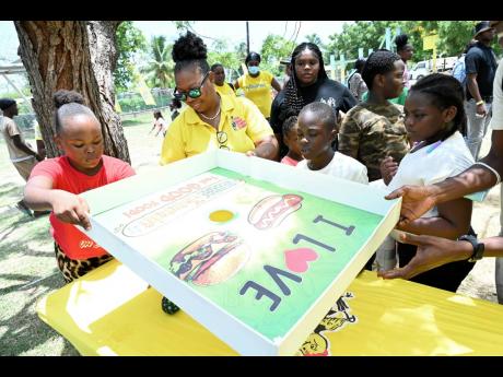 Cyrine Cargill (second left), HR and community liaison officer at Jamaica Broilers Group, plays a game with the children at the Best Dressed Chicken Back-to-School Fair at Spring Village in St Catherine on Thursday.