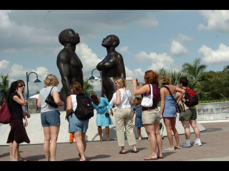 In this file photo, a group of tourists are seen taking photos of the ‘Redemption Song’ statue by artist Laura Facey Cooper outside Emancipation Park in New Kingston. 