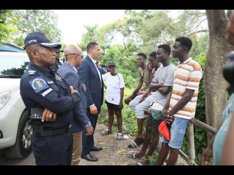 
Prime Minister Andrew Holness speaks with a group of young men from Cherry Tree Lane, Four Paths, Clarendon, where eight persons were killed in a drive-by shooting.
