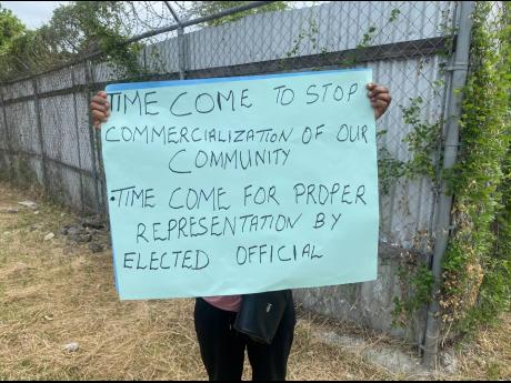 A resident of Richmond Park, St Andrew, holds a placard protesting against a car dealership being set up in the residential community.