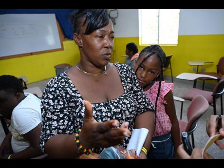 Donnette Brown speaks of the struggle to prepare for the new school year amid an economic crunch as her daughter Gabrielle Lawrence looks on during a fair in Spring Village, St Catherine, last week.