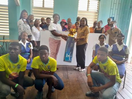 President of the Rusea’s High School 5C graduating Class of 1997, Dr Maureen Nelson (centre left), presenting principal of the school, Mrs Donna Anderson (centre right) with items for the 5C classroom, while present and former students and some teachers 