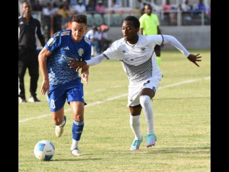 Cavalier FC’s Dwyane Allen (rght) goes in chase of Mount Pleasant FC’s Jean Ferreira during their Concacaf Caribbean Cup football match at Sabina Park yesterday.