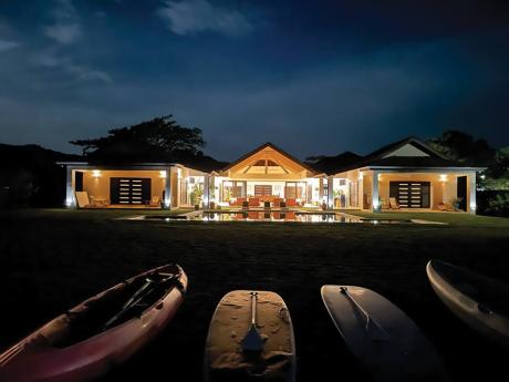 This house is all aglow by the sea at night. 											  