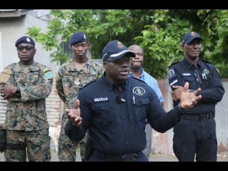 Acting Senior Superintendent Shane McCalla (centre), commanding officer for the Clarendon Police Division, addresses residents ahead of the lighting of the bonfire of remembrance last Friday. He is flanked by (from left) Maj Alwin Forbes and S/Sgt Aba Doug