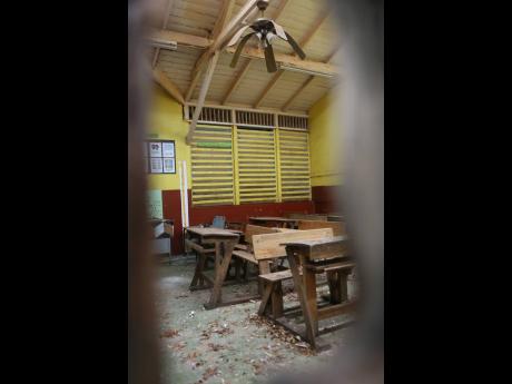 A damaged ceiling fan hovers above furniture in the ravaged grade one block at the New Forest Primary School.