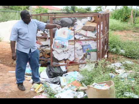 Colin Cameron, principal of Bull Savannah Primary School, shows some of the textbooks that were damaged by Hurricane Beryl in July.