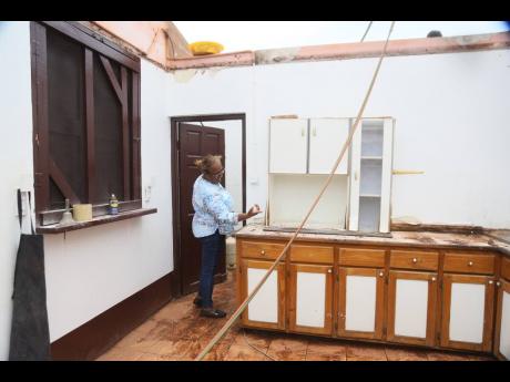 Cavene Headlam, principal of Top Hill Primary School, examining the damage to the cupboards in the kitchen from the passage of Hurricane Beryl in July.