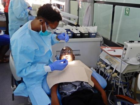 Seven year-old Zachary Wilson, a student at St Ann’s Bay Primary School, is examined by a dentist during the St Ann police health fair and treat.