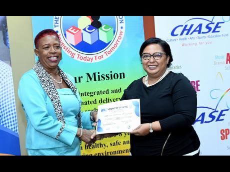 Hilary Coulton (right), public relations and administrative manager of the CHASE Fund, presents a certificate of achievement to Missie Gloria Pennant.