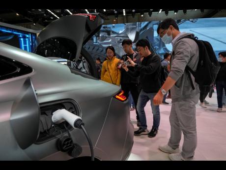 Visitors look at a Geely Galaxy E8 EV car model during the Auto China 2024 in Beijing on April 28, 2024.