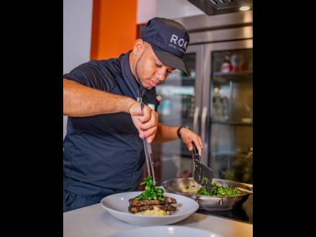 Executive Chef Volae Williams plating the jerk-infused pork lion with yam and potato parmesan ragout and sauteed spinach.