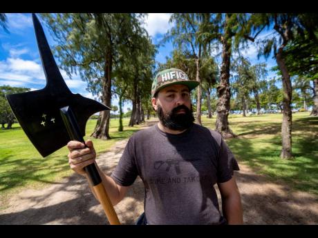 Andrew Roberts, director of the Hawaii Firearms Coalition, poses for a portrait with his halberd while talking to a Honolulu police officer at Kapiolani Park on Saturday, June 22, 2024, in Honolulu, Hawaii.