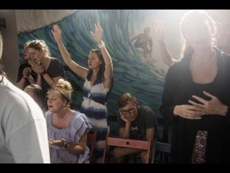 Marielle Louw (raised hands) and Andries Louw, missionaries from South Africa, pray during a worship service at Surf Church in Matosinhos beach in the suburbs of Porto, Portugal.