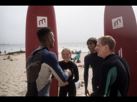 Uliana Yarova (centre) laughs while on a break from surfing with other members of Surf Church Church in Matosinhos beach in the suburbs of Porto, Portugal.