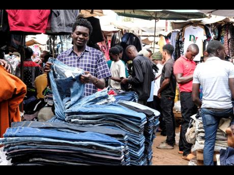 A second-hand-clothes retailer folds second-hand jeans at his stall at Owino Market in Kampala, the capital of Uganda.