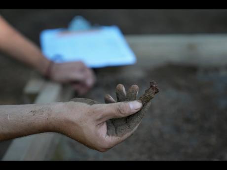 A student holds up what is likely a coffin nail found at an ongoing excavation at the site of an African burial ground in Kingston, N.Y.