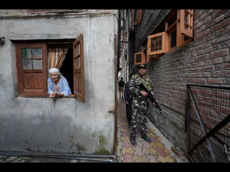 An elderly Kashmiri woman looks on as a paramilitary soldier guard during the door-to -door election campaigning by Bharatiya Janata Party (BJP) candidate ahead of the Jammu and Kashmir state assembly elections, in Srinagar.