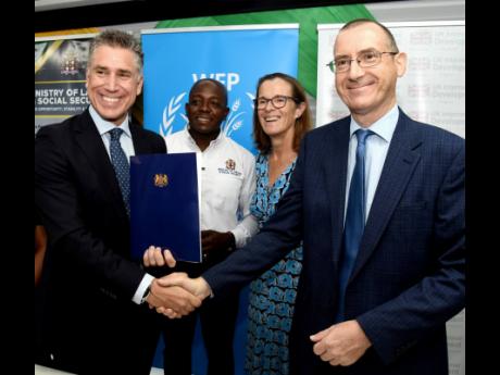 Dana Sacchetti (left), head of the Jamaica Office of the World Food Programme (WFP) Caribbean Multi-Country Office, greets Oliver Blake (right), the United Kingdon Government’s development representative for Jamaica shortly, after signing an MOU for the 