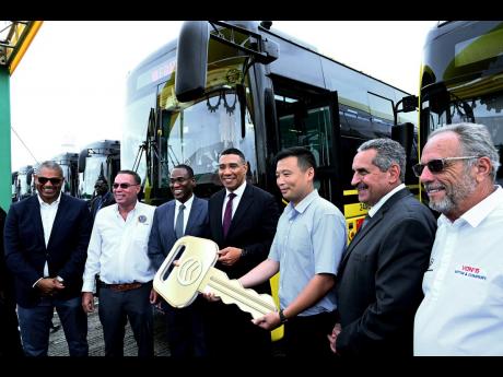 Kevin Wang (third right), vice president of Golden Dragon bus exporting department, presents a symbolic key to Prime Minister Andrew Holness (centre). Looking on (from left) are Mikael Phillips, opposition spokesperson on housing, transport and works; Dary