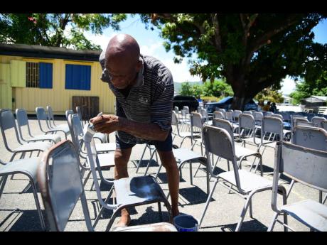 
David Taylor, caretaker at Buff Bay Primary in Portland, paints chairs last Thursday ahead of the school’s reopening on September 2.