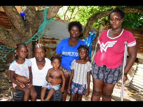 Kenneth Minott, his neice Demetris Powell (centre) and stepdaughter Shantana Dennis with some of the children from his household.