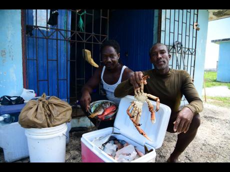 Hope Bay fishermen Trevano Blake (left) and Michael Williams show off a king crab and some fish among their catch at the fishing village last Thursday. With Hurricane Beryl, affecting their livelihoods, they noted that they and many of their colleagues hav