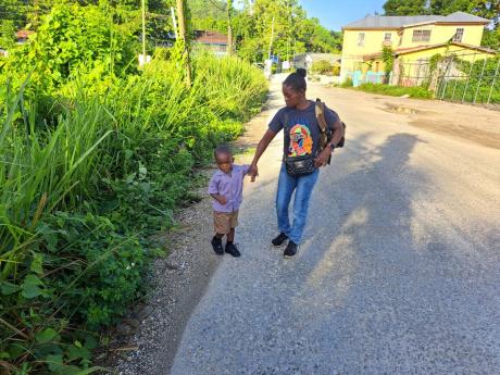 Winsome Anderson, a resident of Adelphi, St James, awaits transportation along the roadway with her grandson ahead of his first day at the Goodwill Primary School on Monday.