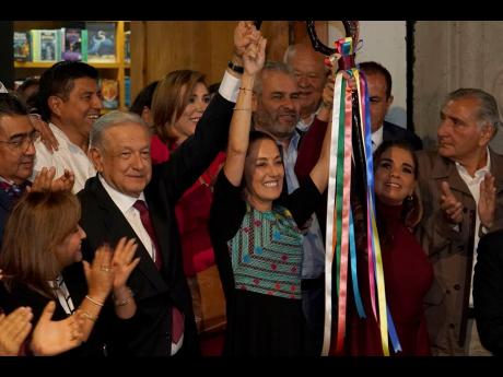 Mexican President Andres Manuel López Obrador raises the hand of Claudia Sheinbaum, the ruling party’s presidential candidate, during a ceremony to give her the party’s command staff in Mexico City on September 7, 2023. 