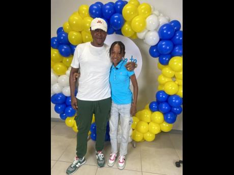 Up-and-coming track and field star, Alzeliha Allen (right), is embraced by her father, Anthony Allen, after she was announced as a Courts Dare to Dream scholarship awardee on Friday at the stores’ corporate offices in Kingston. 