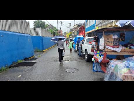 Portlanders carry umbrellas along William Street in Port Antonio, Portland, during yesterday’s heavy rainfall.