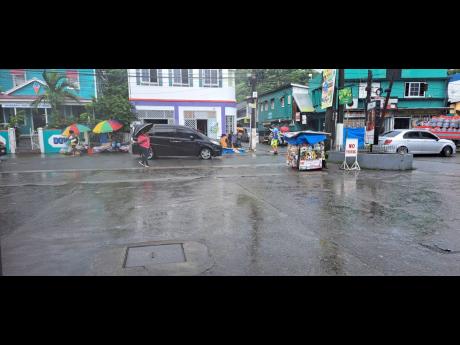 Portlanders carry umbrellas along William Street in Port Antonio, Portland, during yesterday’s heavy rainfall.