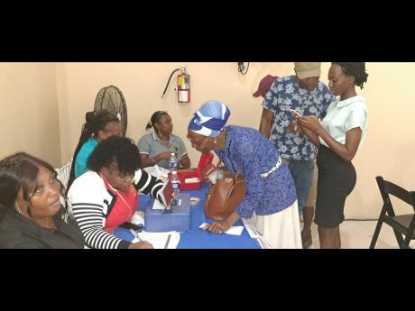 Icilda Nelson signs for a grant to assist with rebuilding her home during the Rebuild Jamaica Handover Tour, which was hosted on Wednesday, at Hotel Tim Bamboo in Portland. 