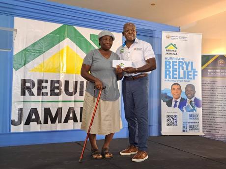  Labour and Social Security Minister Pearnel Charles Jr (right) presents a financial grant to St James resident Mavis Belle, one of 162 beneficiaries from St James and Hanover who received grants through the ministry's Rebuild Jamaica Programme, at the Mon