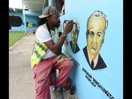 Robert Dawson spraybrush the faces of the National Heroes on the wall at the Elite Basic School in Seaview Gardens, ahead of the new school term.