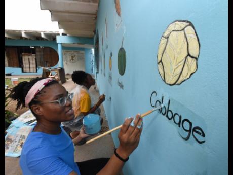 Esther Ehikhamenor (front) and Alesha McDonald carefully brighten up the artwork on the walls.