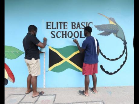 Antoine Lodge (left) lead volunteer and founder of the Dream Big For Youth Foundation and his senior volunteer, Michael Paul Dixon, paints a section of the wall. 