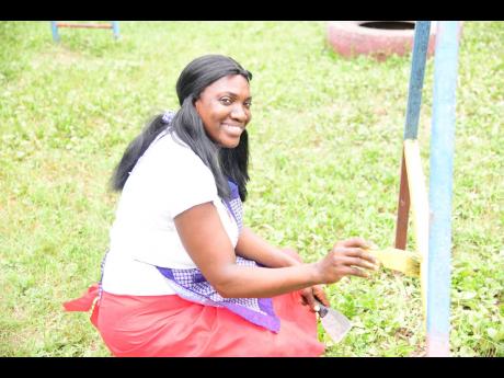 Natoya Simmonds-Berry, a class one teacher at Elite Basic School, happily paints part of the playground slides.