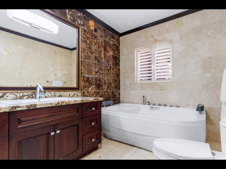 A bathroom clad in rich marble and granite with its own spa tub.