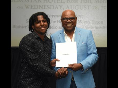 
Jevon McKenzie (left), a student of the Edna Manley College of the Visual and Performing Arts and a beneficiary of the East Central St James Scholarship Fund, collects his award from Edmund Bartlett, member of parliament for St James East Central and foun