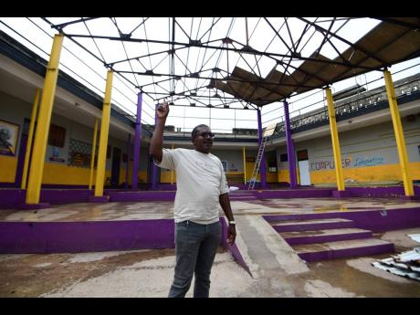 Teacher Devon Wilson highlights the damage to the school's auditorium area caused by Hurricane Beryl.