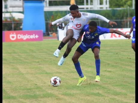 Mona High School’s Denzel McKenzie (left) tries to evade the challenge of Waterford High School’s Jaheek Hull Blake during their ISSA/WATA Manning Cup fixture at the Montego Bay Sports Complex yesterday. 