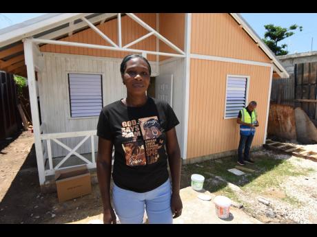 Latoya Alison Gilepsy stands before the brand-new house she received from Donnie McClurkin, American gospel singer and pastor, in partnership with Food For The Poor Jamaica, on Wednesday. She and her five children are 2004 fire victims.  