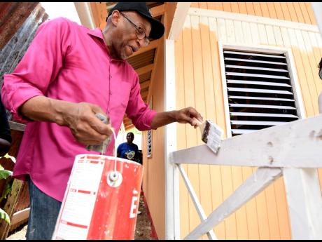 Donnie McClurkin, popular American gospel singer and pastor, painting a railing on the house he paid Food For The Poor Jamaica to construct for 2004 fire victim Latoya Gilepsy. 