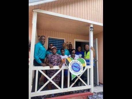 Kingston Properties Limited hands over a house on Wednesday in Callaloo Mews which it built in partnership with Food For The Poor Jamaica. Here, representatives (back row from left) Kevin Richards, Tanesha Rowe, Andray Francis, Tanya Williams-Thompson, Jov