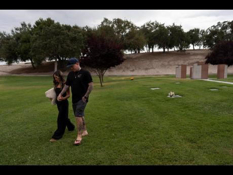 Mikayla Brown, left, and her husband, Tyler, hold hands as they walk toward their car after visiting the grave of their son, Elijah, who died of a fentanyl overdose at 15, in Paso Robles, California.