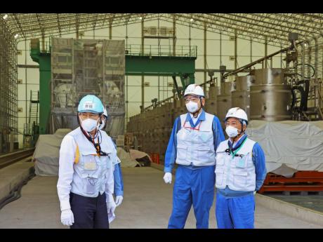 Japanese Prime Minister Fumio Kishida, left, along with Tomoaki Kobayakawa, president of Tokyo Electric Power Co. (TEPCO), second right, and Yoshimitsu Kobayashi, chairman of TEPCO, visits a facility to treat radioactive wastewater at the tsunami-wrecked F